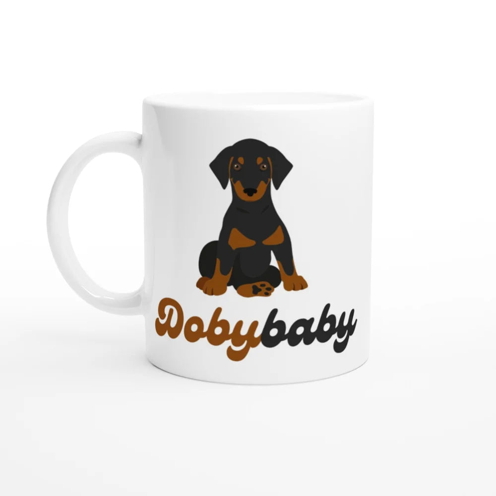 Tasse en céramique blanche représentant un chiot Doberman assis et le texte ’Dobybaby’ en lettres brunes.