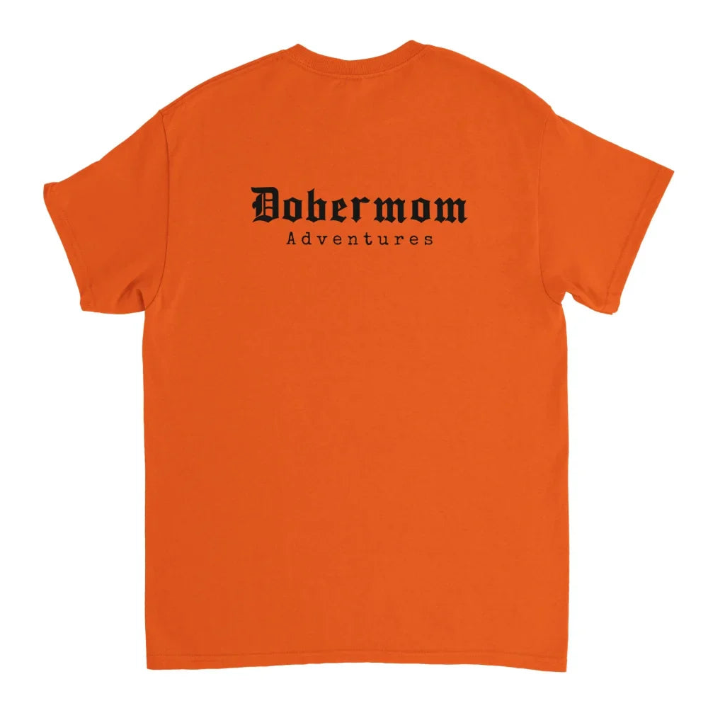 T-shirt orange avec ’Dobermom Adventures’ imprimé au dos en texte noir.